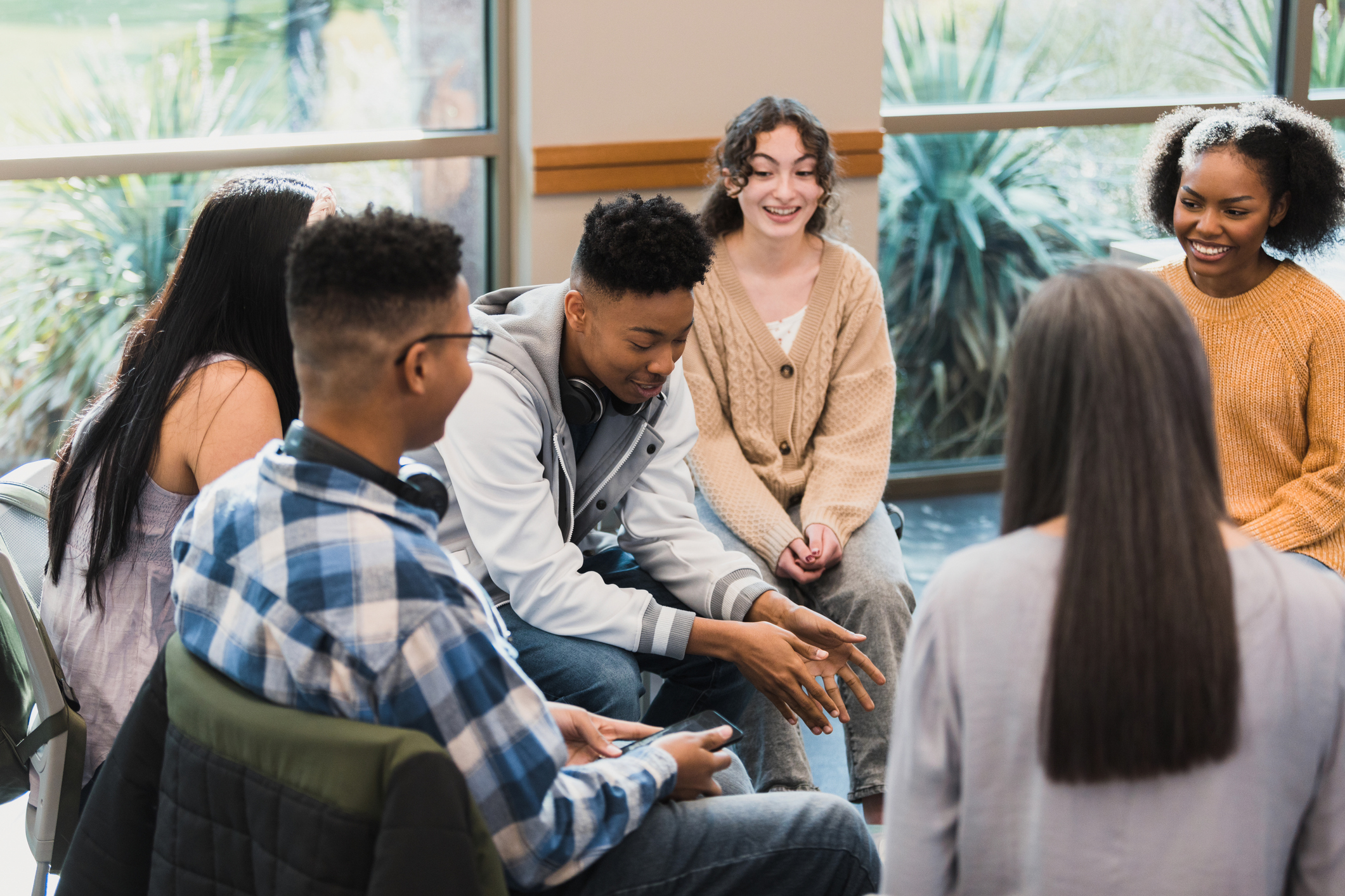 The group of peers listen proudly as their friend talks about a difficult time in his life.